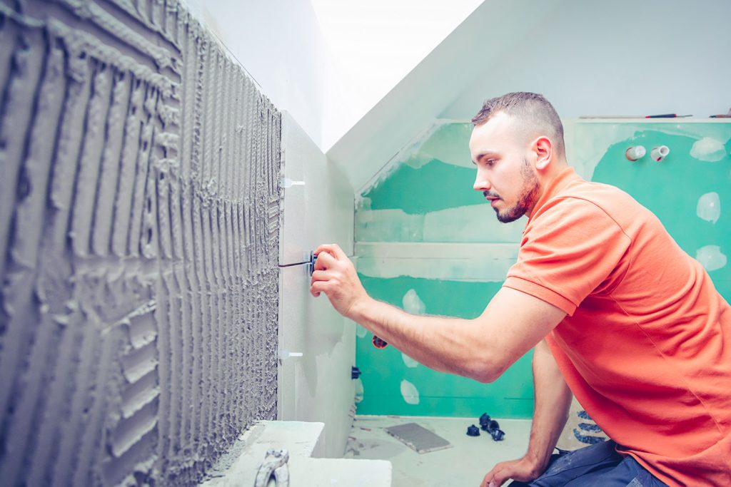 homme place nouveaux carrelages pendant rénovation de salle de bains