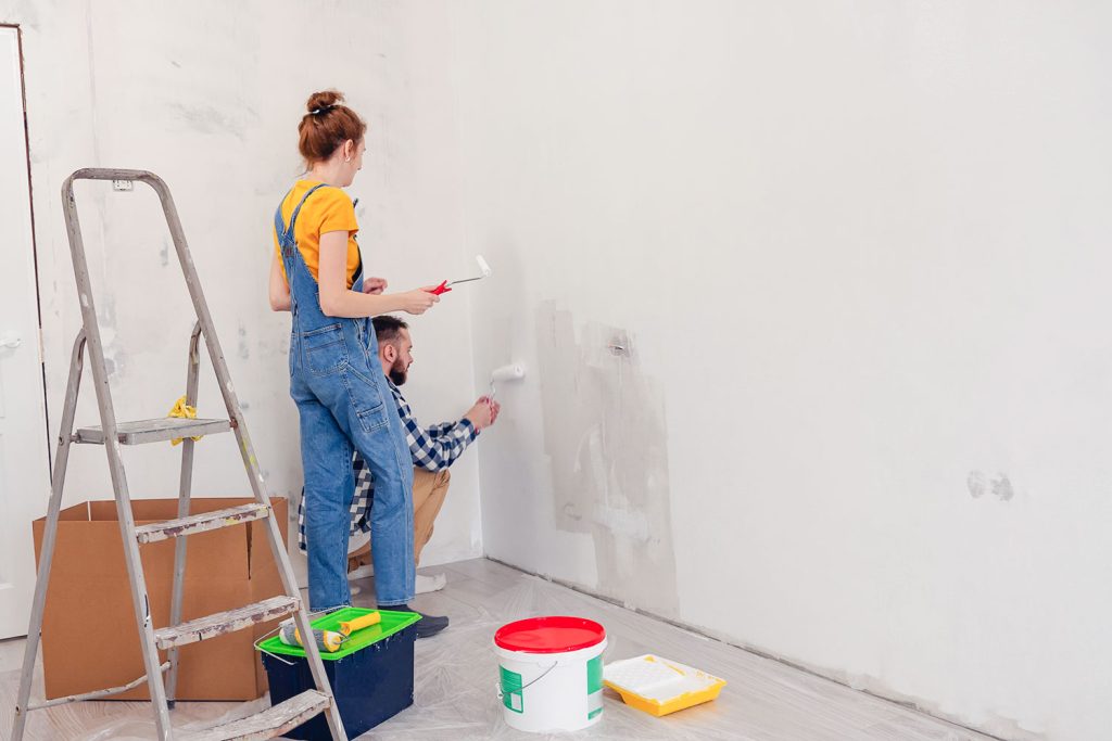 un jeune couple peint un mur