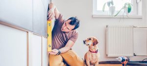 Homme dans son logement en train de prendre des mesures avec son chien