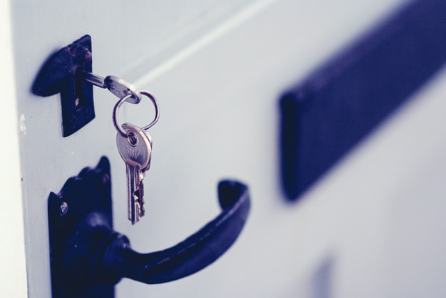 Sleutelbos met één sleutel in het slot van een deur gestoken