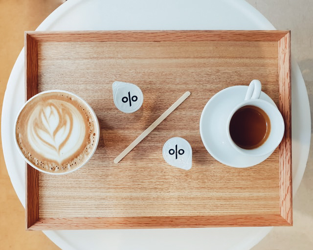 2 tasses de café sur un plateau avec le signe pourcent représenté sur les couvercles des laits