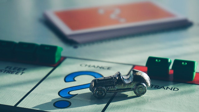 Monopolyspel met het autostuk en de huizen op de achtergrond