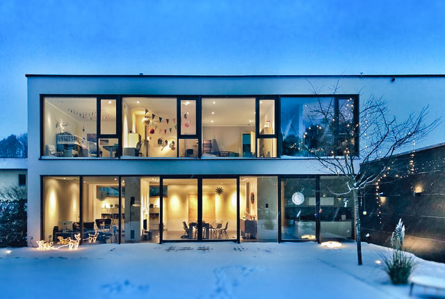 modern huis met grote ramen en een besneeuwde tuin