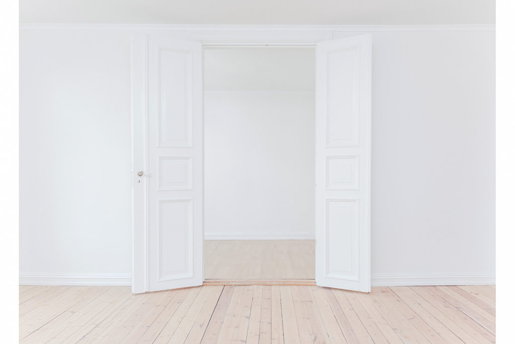 leeg appartement met witte houten deur en parketvloer