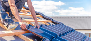 dakwerker plaatst nieuwe dakpannen tijdens dakrenovatie