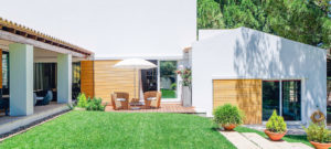 moderne woning met witte gevel, houten gevelbekleding en gras in de zon