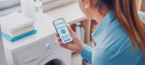 vrouw bedient slimme wasmachine met smartphone app