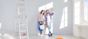 couple planifie rénovations dans une pièce claire ensoleillée avec ustensiles de peinture et une échelle