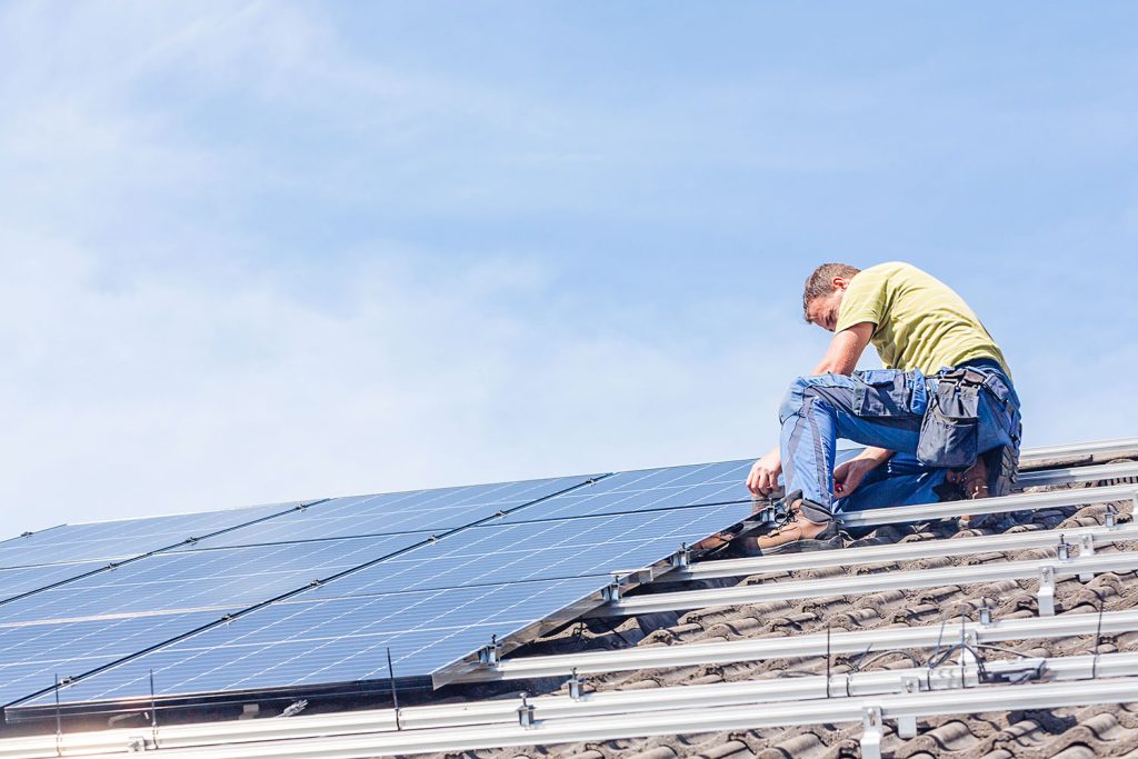 man installeert zonnepanelen op hellend dak