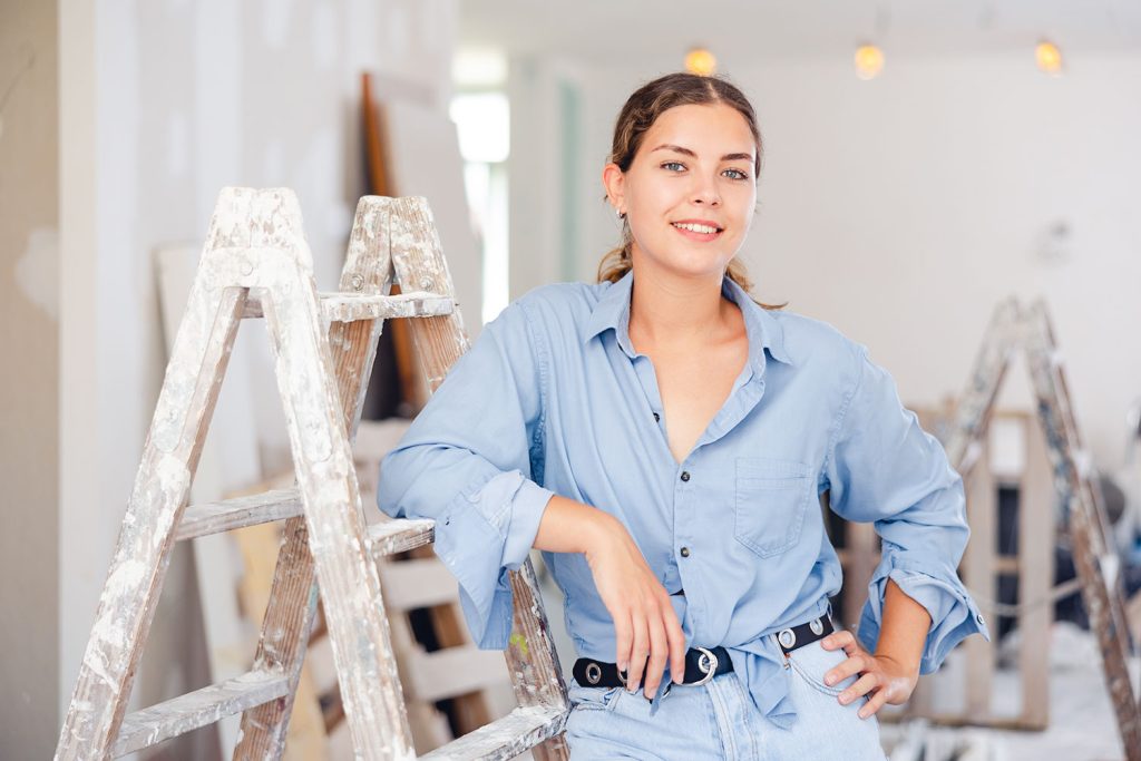 jonge vrouw leunt op ladder tijdens renovatie huis