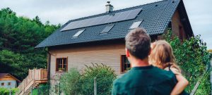 man en kind kijken naar houten woning met zonnepanelen