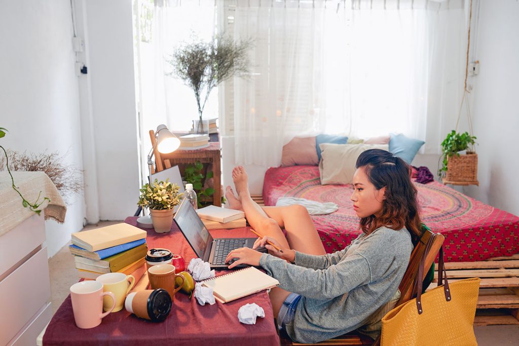 jeune étudiante travaille avec portable dans sa chambre