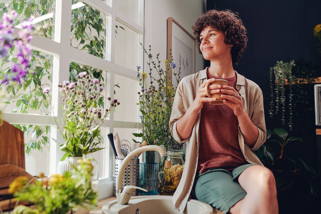 femme assise dans la cuisine entourée de plantes