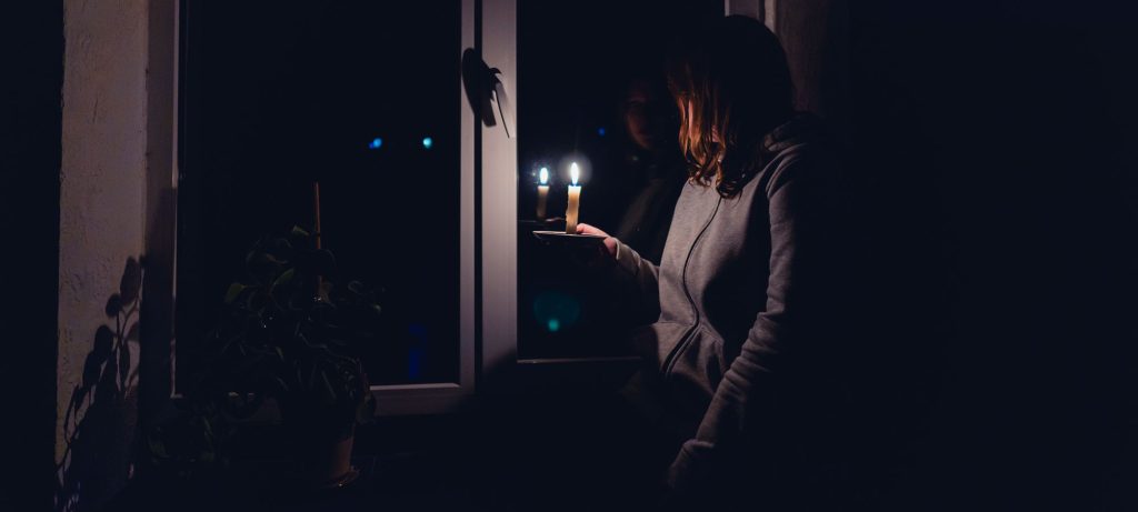 Femme avec une bougie en main pendant une panne complète d’électricité