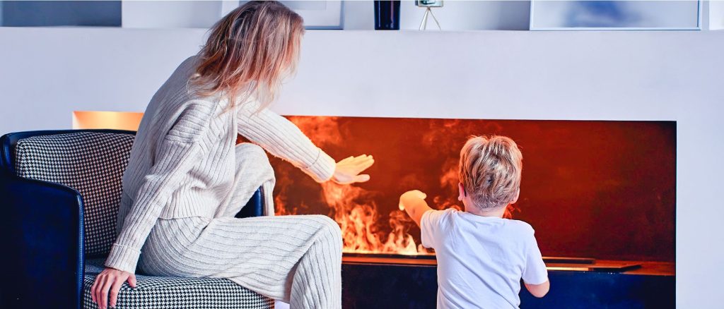 mère et fils assis face à un foyer électrique