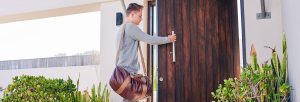 Un jeune homme se tient devant la porte d'entrée pour la réparation de la sonnette.