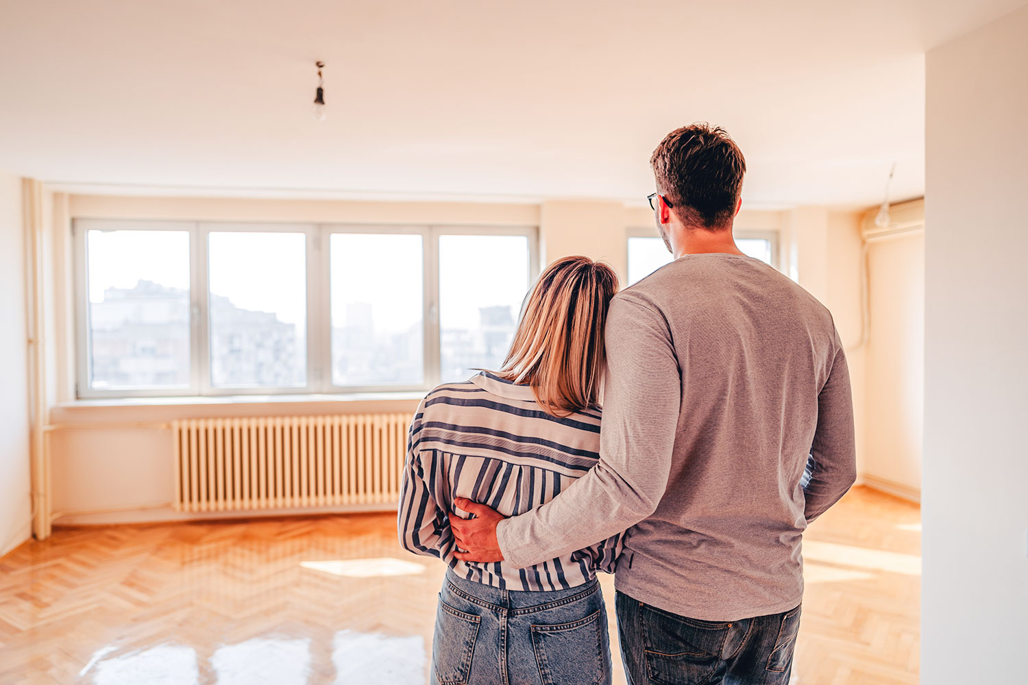 Couple admire ensemble le living vide d’une maison