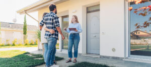 Couple devant une porte d’entrée avec agent pour visiter maison